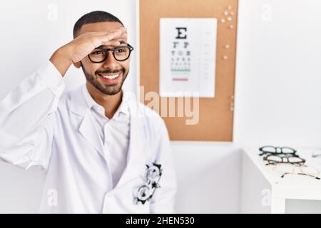 Un opticien afro-américain debout avec la vue teste très heureux et souriant regardant loin avec la main sur la tête. Concept de recherche. Banque D'Images