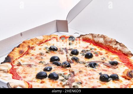 Une seule pizza italienne anchois sur une boîte de livraison isolée sur fond blanc Banque D'Images