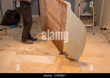 Le travailleur de la construction enlève l'ancien plancher stratifié pour réparer et installer le parquet dans la maison Banque D'Images