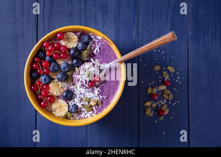 Bol à smoothie aux fruits sains et crus sur une surface en bois bleu avec espace de copie Banque D'Images