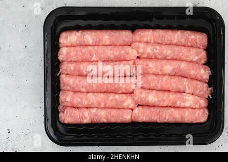 Saucisses de petit-déjeuner au poulet dans un contenant en plastique noir, étales à plat avec espace pour les copies Banque D'Images