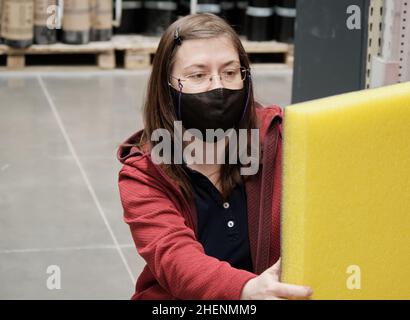 Une femme dans un magasin de matériaux de construction choisit jaune, isolation insonorisée à acheter Banque D'Images