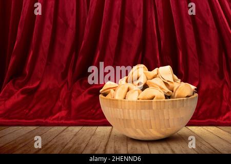 Biscuits fortune dans le bol en bois avec fond de rideau rouge.Bonne année chinoise Banque D'Images