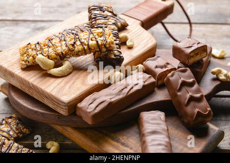 Planches avec de savoureuses barres de noix de chocolat sur fond de bois Banque D'Images