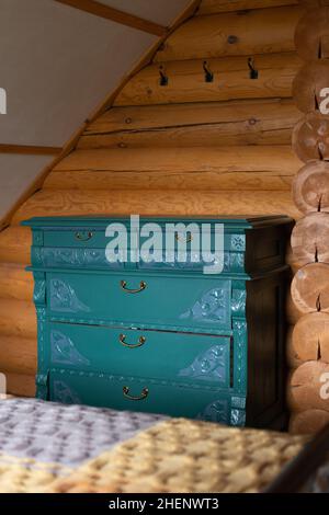 Ancienne commode rénovée peinte turquoise avec ornements sculptés et prête pour une réutilisation écologique dans une maison de campagne en bois Banque D'Images