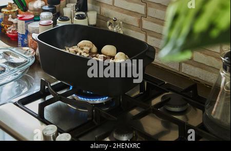 Un gros morceau de bœuf aux champignons est frit dans du chou-fleur spécial sur un poêle à gaz Banque D'Images