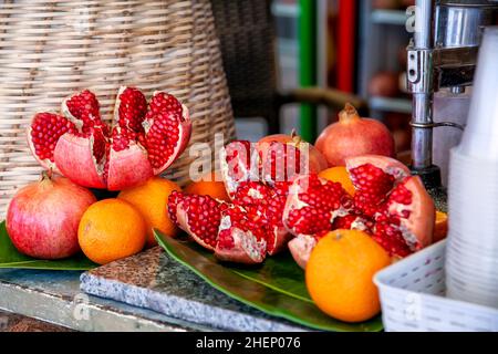 Fruits de grenade brisés et oranges entières et grenades, préparés pour du jus fraîchement pressé sur le comptoir du commerce de rue. Banque D'Images