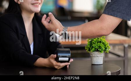 Image rognée de l'homme d'affaires qui fait un paiement en utilisant une montre intelligente avec un café flou comme arrière-plan.concept de technologie NFC Banque D'Images