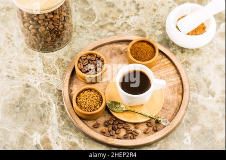 plateau rond en bois avec une tasse de café, des grains de café et du café lyophilisé dans des bols. bol en verre avec grains de café, mortier pour broyage Banque D'Images