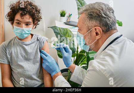 Enfant de sexe masculin pendant la vaccination dans le cabinet du médecin.Vaccination des enfants en cas de pandémie mondiale Banque D'Images