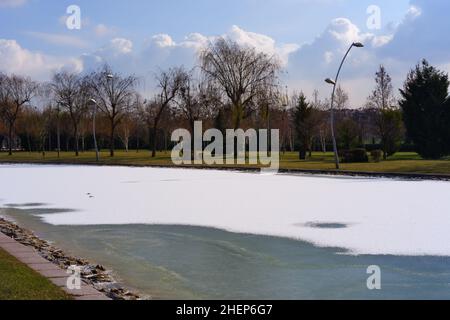 Lac artificiel partiellement gelé et fontaine dans un parc de la ville Banque D'Images