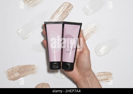 Tubes en plastique avec cosmétiques sur fond crème Banque D'Images