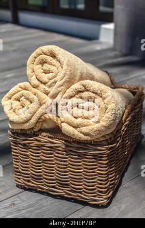 Trois rouleaux de serviettes beige dans un panier en rotin de chaume.Image verticale. Banque D'Images