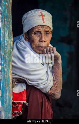 Vieille femme éthiopienne avec Croix-Rouge sur le Cap regardant de la porte Banque D'Images