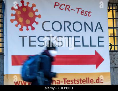 Munich, Allemagne.12th janvier 2022.Une femme passe devant les panneaux au Deutsches Museum et pointe vers une station d'essai de Corona.Credit: Peter Kneffel/dpa/Alay Live News Banque D'Images