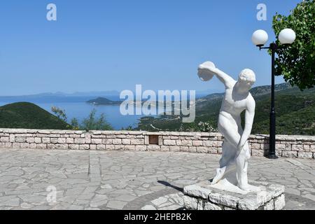 Perdika, Grèce - 29 juin 2021 : sculpture d'un lanceur de discus sur la place principale du village de montagne d'Epire avec la mer Ioanienne en arrière-plan Banque D'Images