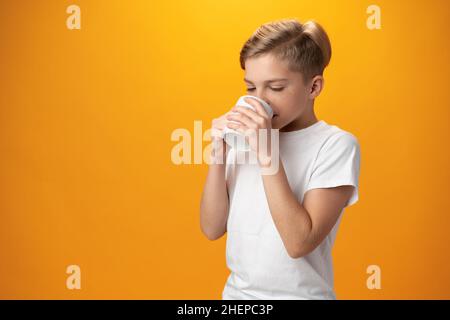 L'enfant boit du cacao chaud sur fond jaune Banque D'Images