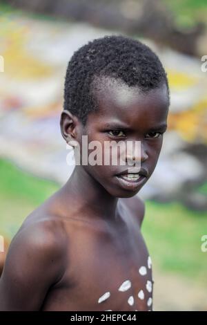 Gros plan de portraits de jeunes garçons de la tribu des bennés avec peinture traditionnelle du corps sur les longues bâtons en bois Banque D'Images