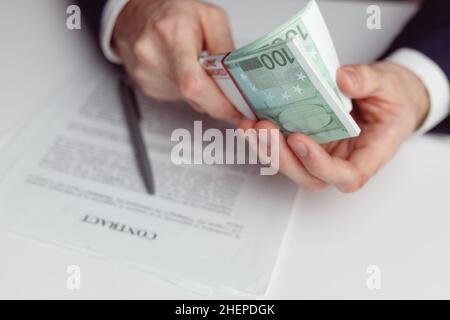 L'homme en costume compte de l'argent avant de signer le contrat.Gros plan avec de l'argent euro Banque D'Images