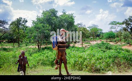 Tribu de Hamer fatiguée les femmes qui reviennent du travail agricole par la route rurale verte Banque D'Images