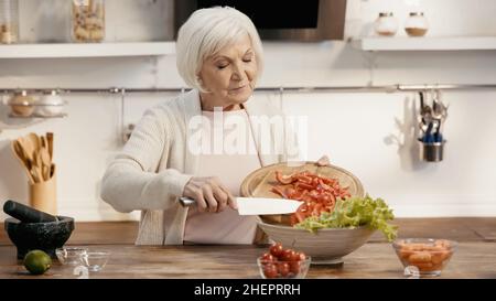 femme âgée ajoutant du poivron en tranches à la salade de légumes pour le dîner d'action de grâce Banque D'Images