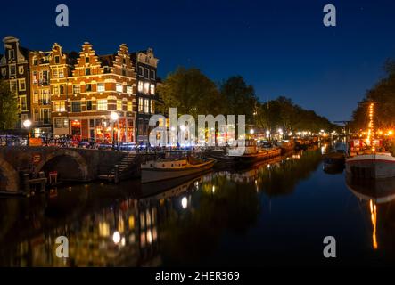 Pays-Bas.Canal nocturne d'Amsterdam et ciel sans nuages.Les barges et les bateaux résidentiels sont amarrés avec réflexion dans l'eau Banque D'Images