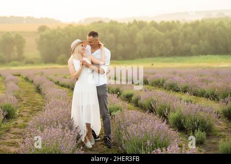 Un couple aimant debout dans un champ de lavande et embrassant Banque D'Images