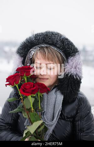 Femme avec des roses rouges dehors en hiver Banque D'Images