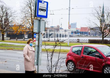 RIGA, LETTONIE.12th novembre 2020.Photo à mise au point sélective.Femme portant un masque facial à l'arrêt de bus. Banque D'Images