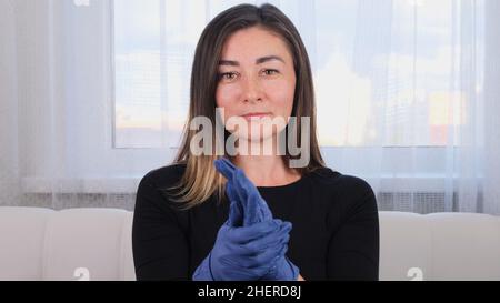 Femme en gants de protection bleus utilisant un gel désinfectant pour laver les mains pour prévenir les épidémies virales ou les agents antibactériens. Banque D'Images