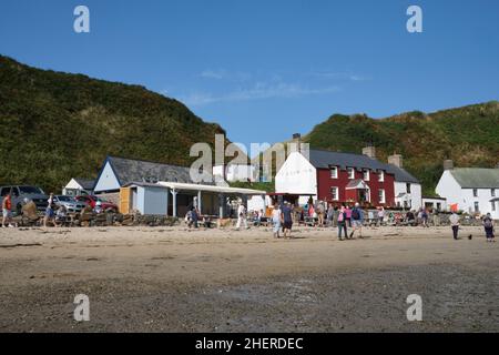 Les touristes se rassemblent en face de l'auberge Ty Coch sur la plage dans le village de Porth Dinllaen, au nord du pays de Galles Banque D'Images