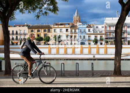 Les cyclistes équitation le long des rives du fleuve Guadalquivir. Retour vue avant de maisons et d'appartements dans le quartier Triana de Séville - Séville Banque D'Images