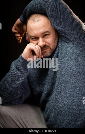 Homme d'âge moyen dans un chandail regardant la caméra.Homme non rasé d'apparence normale. Banque D'Images