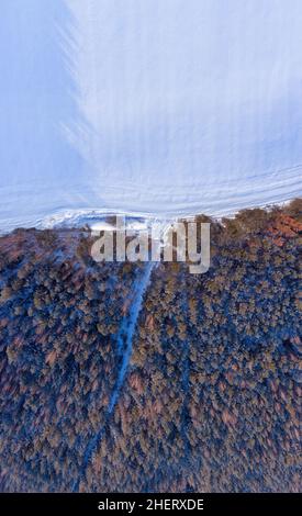 Paysage aérien d'hiver.Le givre enneigé couvrait la forêt et le champ avec des pistes dans la neige. Banque D'Images