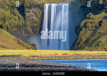 Longue exposition de la cascade de Skogafoss en Islande depuis la rivière de distance Banque D'Images