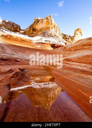 Rare, la neige sur des roches rouges se reflète dans l'eau dans une alcôve de la zone de White Pocket du monument national de Vermilion Cliffs, en Arizona. Banque D'Images