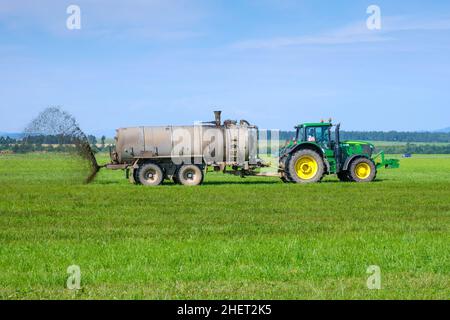 Un gros tracteur qui épandre de l'engrais pour améliorer la récolte sur les pâturages.Concept d'agriculture terrestre.Janvier 2022, Poprad, Slovaquie. Banque D'Images