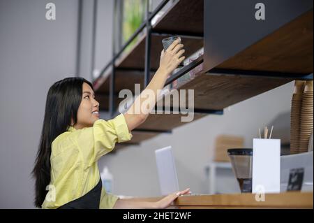 Une jeune femme asiatique écrit un menu à bord dans un café Banque D'Images