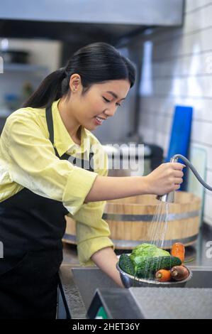 Femme dans la cuisine laver les légumes avant de cuisiner Banque D'Images