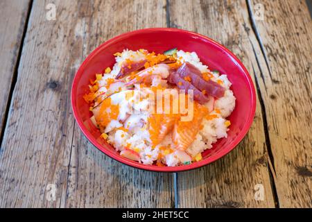 Cuisine japonaise asiatique : saumon, thon, sushis de crevettes et de calmars, fruits de mer crus servis dans un bol de riz Banque D'Images