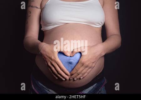 c'est un garçon coeur bleu avec les mains sur le ventre de la mère enceinte Banque D'Images