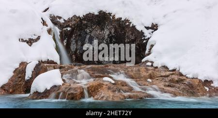 chute d'eau froide et glacée entre les rochers dans la neige d'hiver Banque D'Images