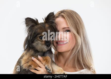 Une jeune fille embrasse son chien qu'elle tient dans ses bras.Portrait d'une femme et d'un chien.Chien de race multiple. Banque D'Images