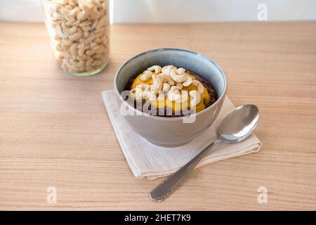 Végétalien, sans gluten.Porridge coloré dans un bol avec garniture aux noix de cajou sur la table en bois.Petit déjeuner sain. Banque D'Images