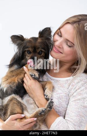 Le chien lèche son nez.Une fille tient un chien dans ses bras.Portrait d'une femme avec un chien.Chien de race multiple. Banque D'Images