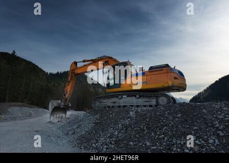 vue latérale d'une pelle-pelle-excavatrice orange énorme creusant dans le gravier Banque D'Images