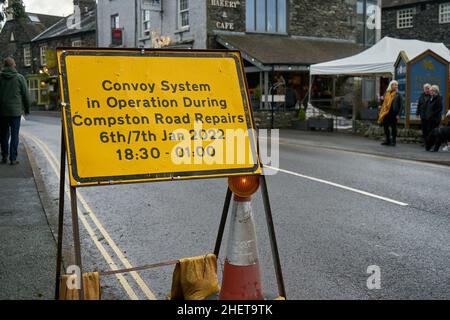 Panneau jaune avec texte noir avec des informations sur un système de convoi de circulation et ses heures de fonctionnement pour les réparations de routes Banque D'Images