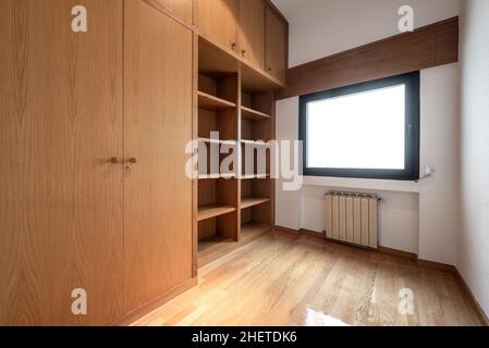 Cette chambre vide dispose d''une armoire et d''une bibliothèque en chêne, de parquet en chêne et d''un radiateur en aluminium sous la fenêtre Banque D'Images