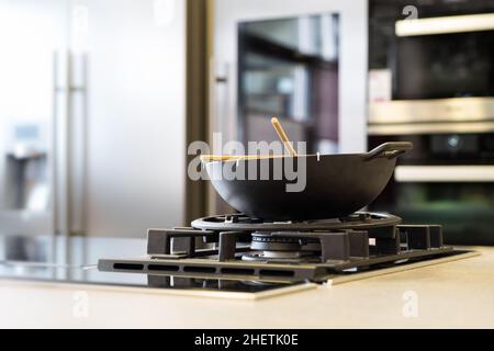 un wok de nouilles sur cuisinière à gaz sur une plaque de travail dans une cuisine moderne Banque D'Images