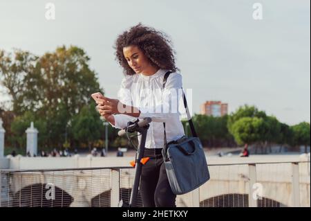 Une jeune femme télécharge l'application pour utiliser le scooter électrique en ville rue saine style de vie durable style de vie Banque D'Images